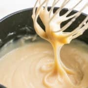 A whisk dripping vegan custard from a saucepan.