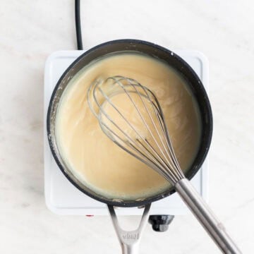 Milk, cornstarch, and sugar mixture cooking in a saucepan until thickened.