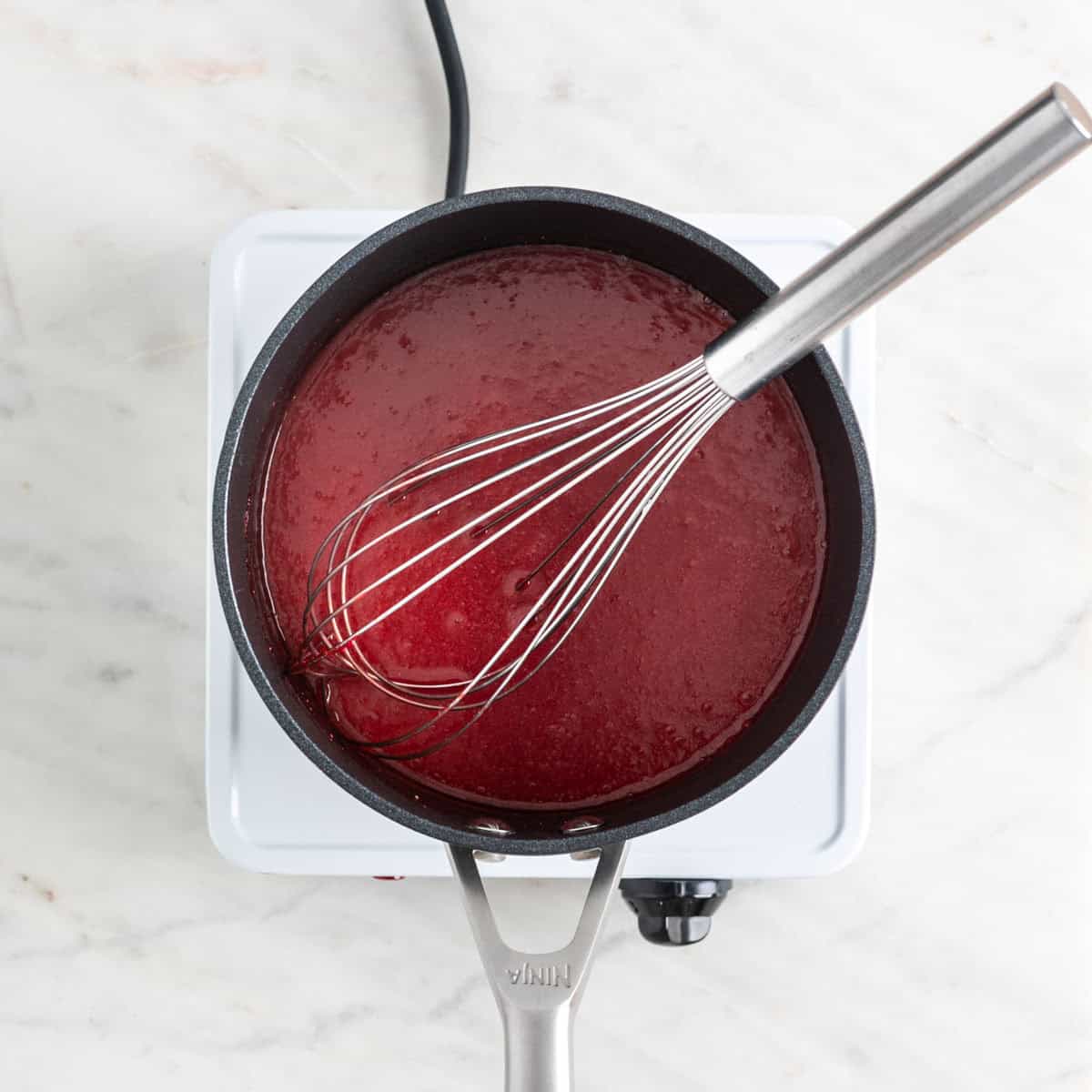 Cooked strawberry coulis in a saucepan.