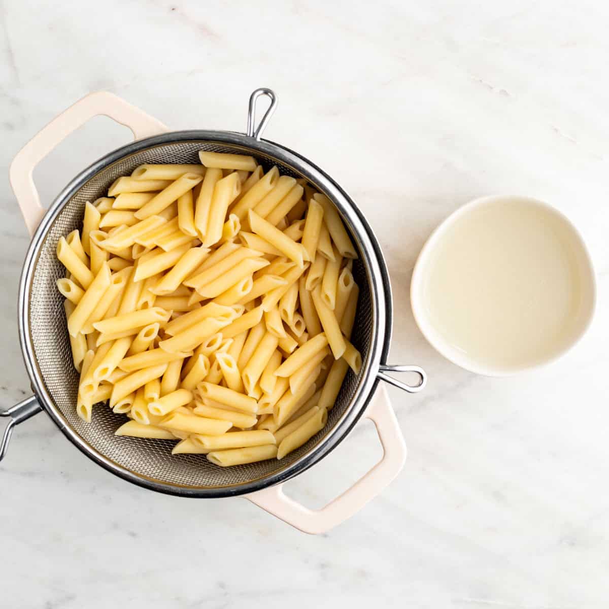 Cooked pasta in a pot and reserved pasta water in a bowl.