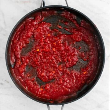 Sautéed onion, garlic, tomato paste, salt, pepper, vodka, and reserved pasta water in a skillet.
