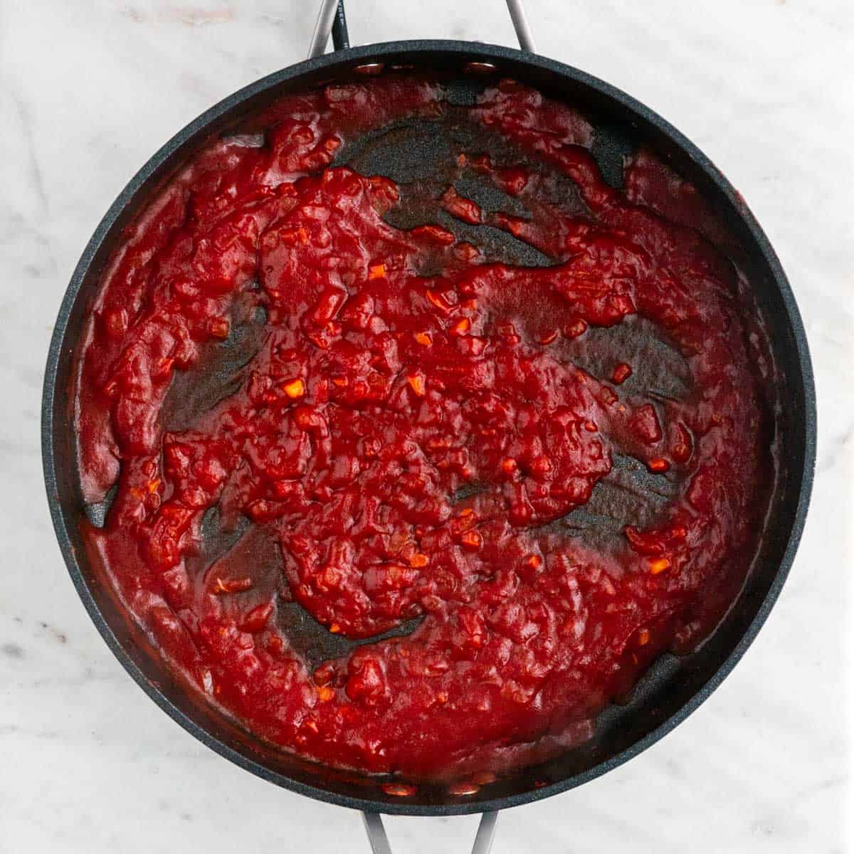 Sautéed onion, garlic, tomato paste, salt, pepper, vodka, and reserved pasta water in a skillet.