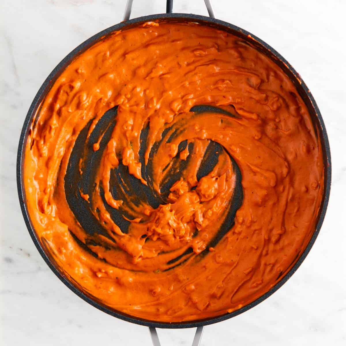 Vegan vodka sauce in a skillet before adding vegan butter and parmesan cheese.