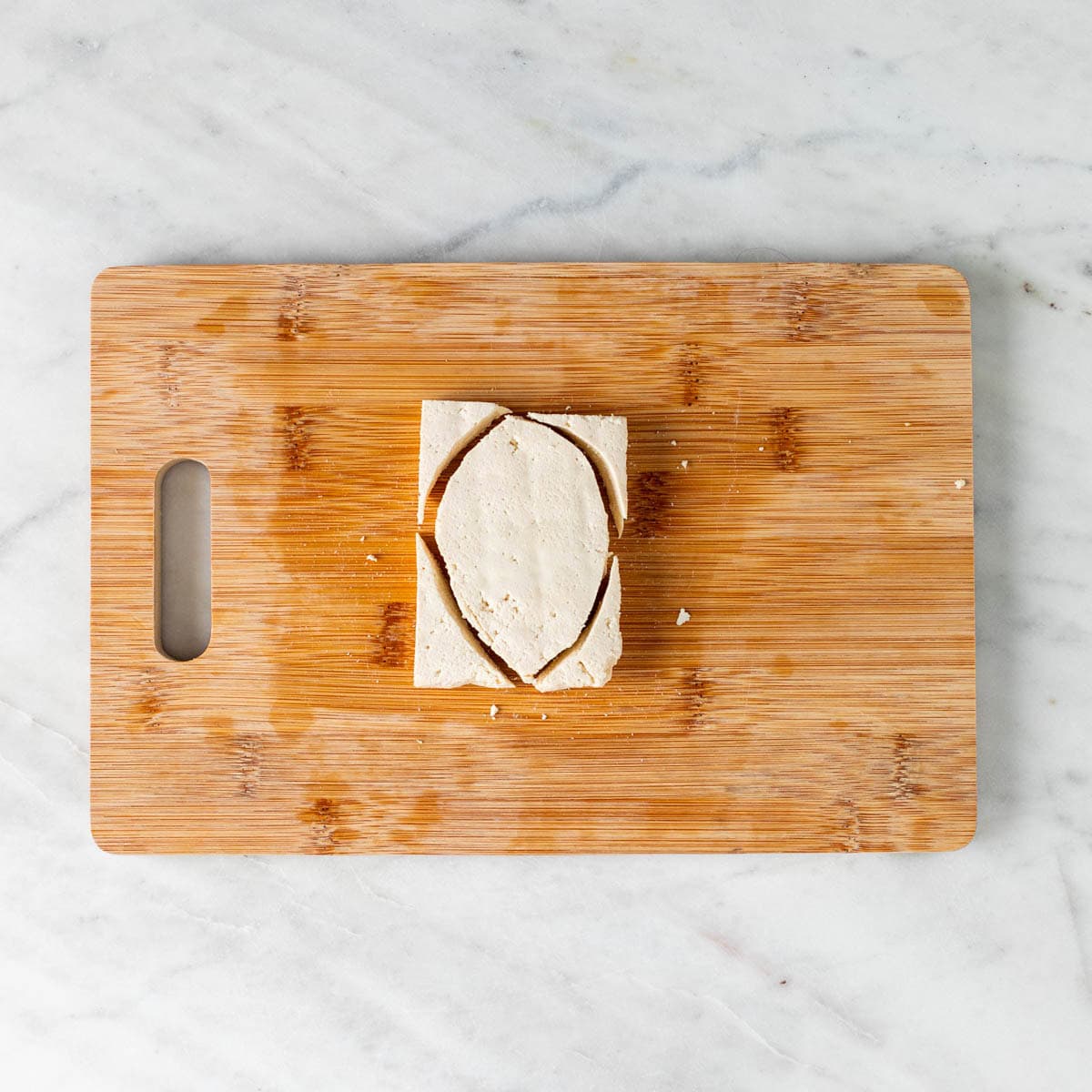 Tofu filet chopped into chicken breast shapes on a wooden cutting board.