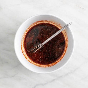 Marinade in a bowl with a mini whisk.