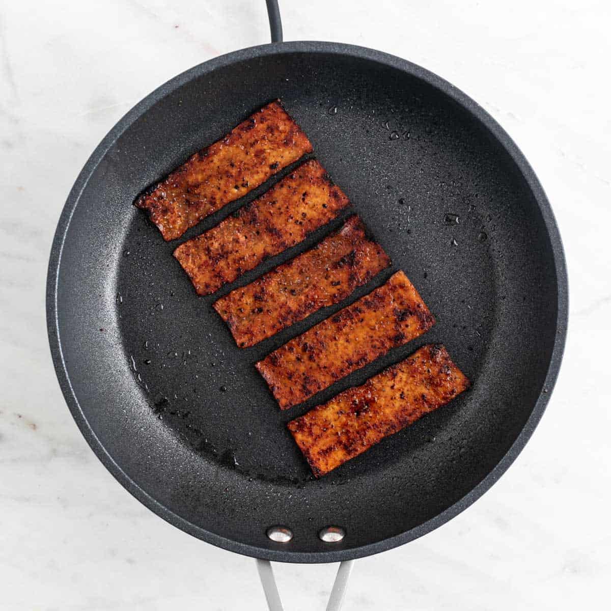 Cooked tofu bacon in a skillet.