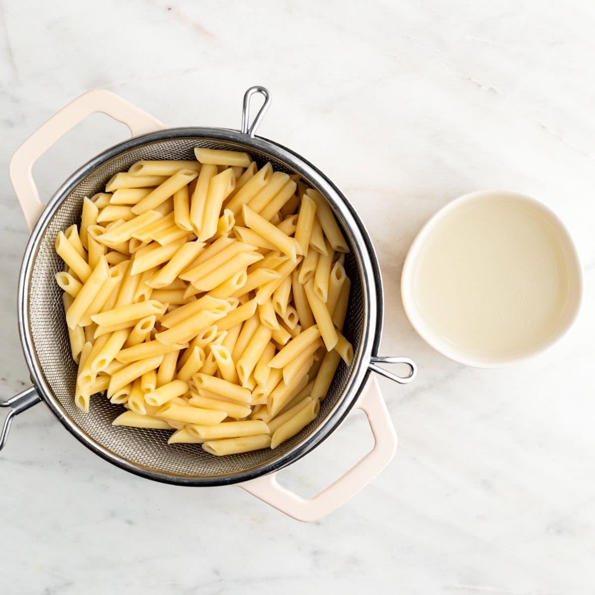 Cooked pasta in a pot and reserved pasta water in a bowl.