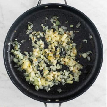 Sautéed onion and garlic in a skillet with red pepper flakes.