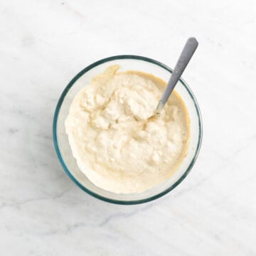 Vegan blue cheese dressing in a bowl with a spoon inside.