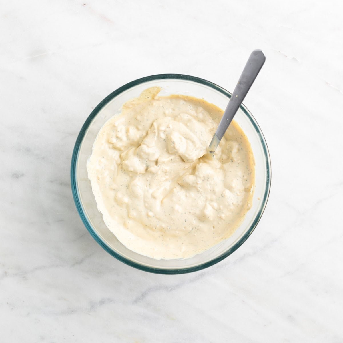 Vegan blue cheese dressing in a bowl with a spoon inside.