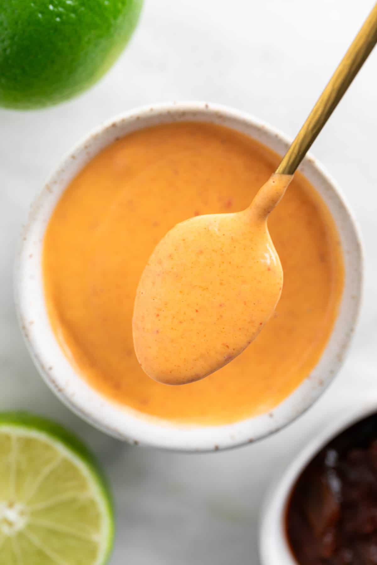 Spoon scooping vegan chipotle mayo from a bowl.