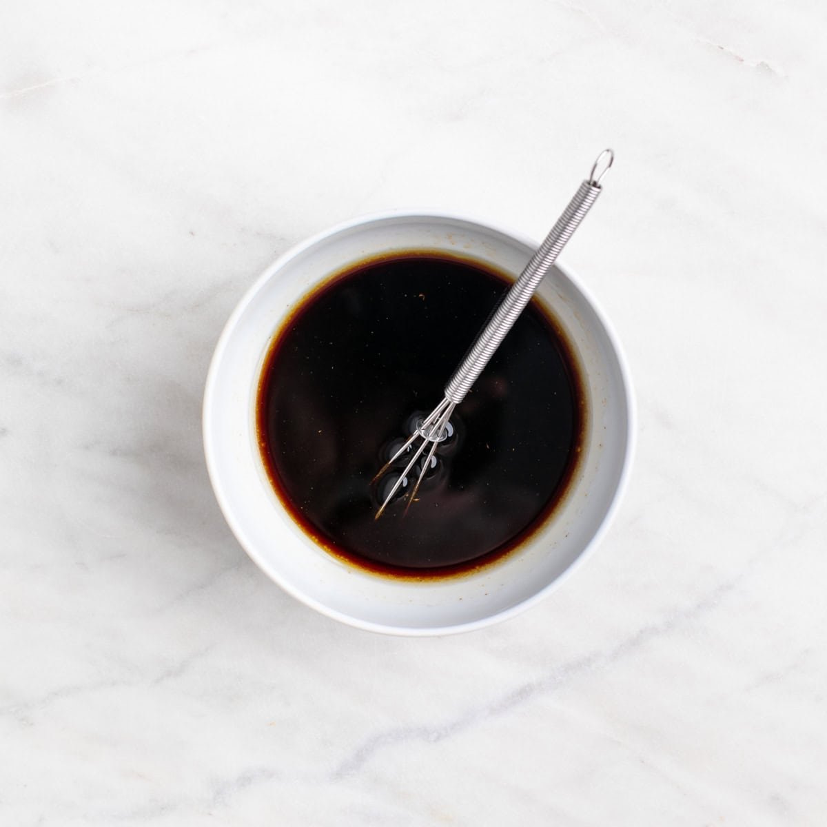 Marinade in a bowl with a whisk.