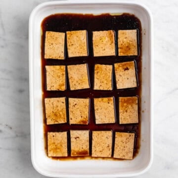 Tofu slices marinating in a baking dish.