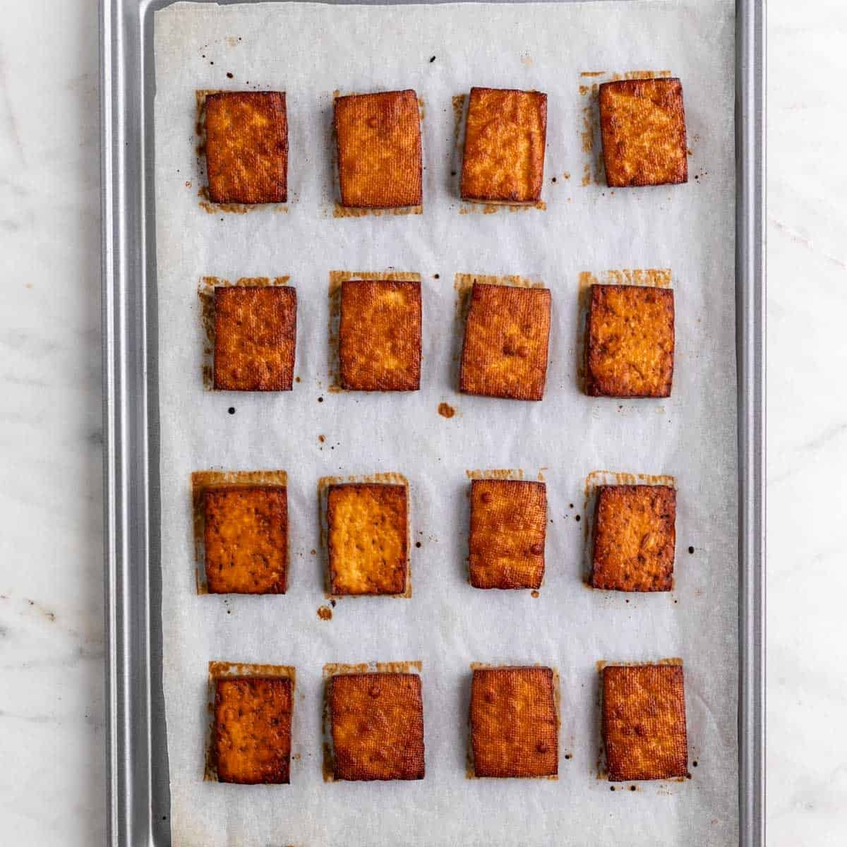 Baked tofu slices in a lined baking dish.