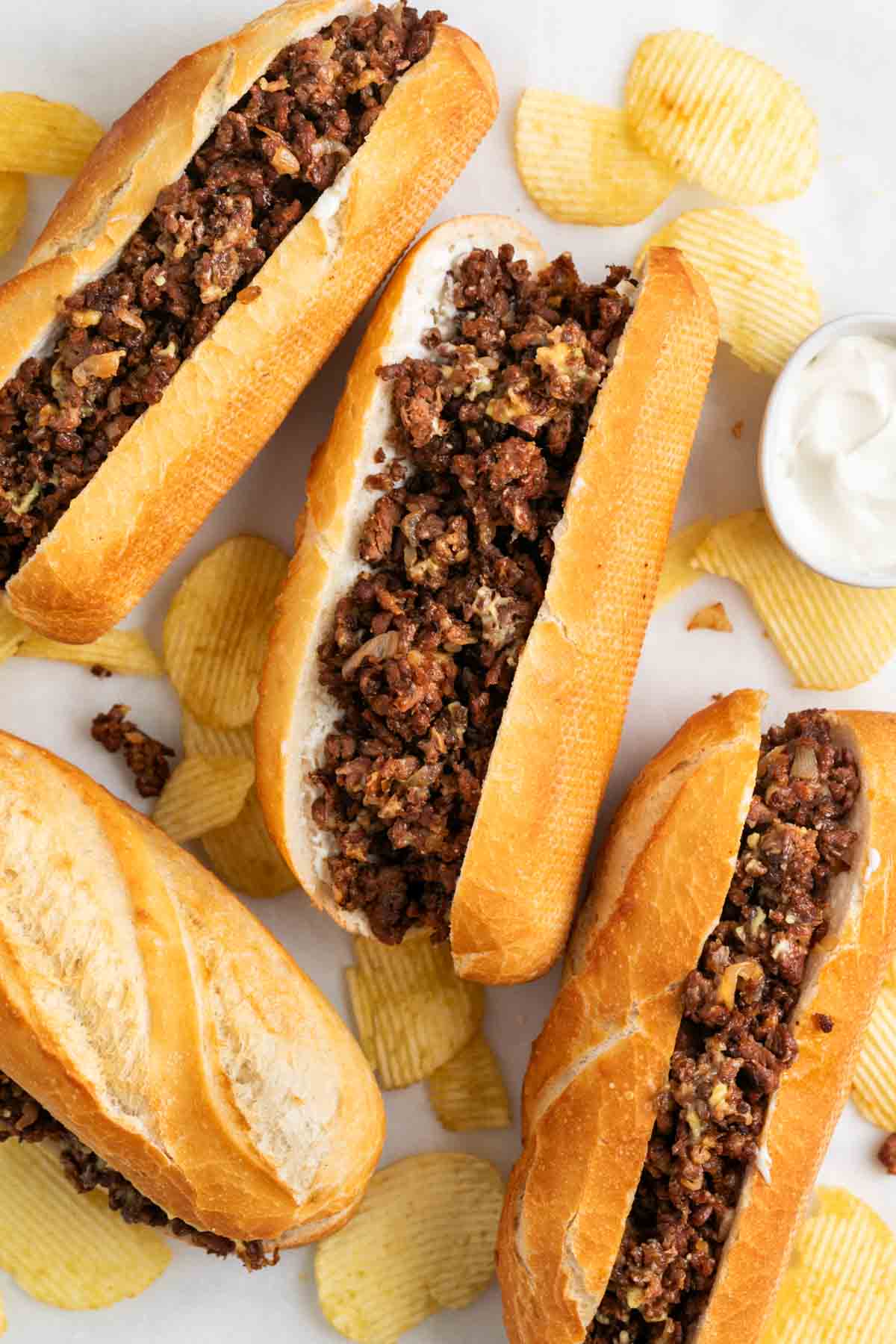 Vegan Philly cheesesteak sandwiches served with chips and vegan mayo.