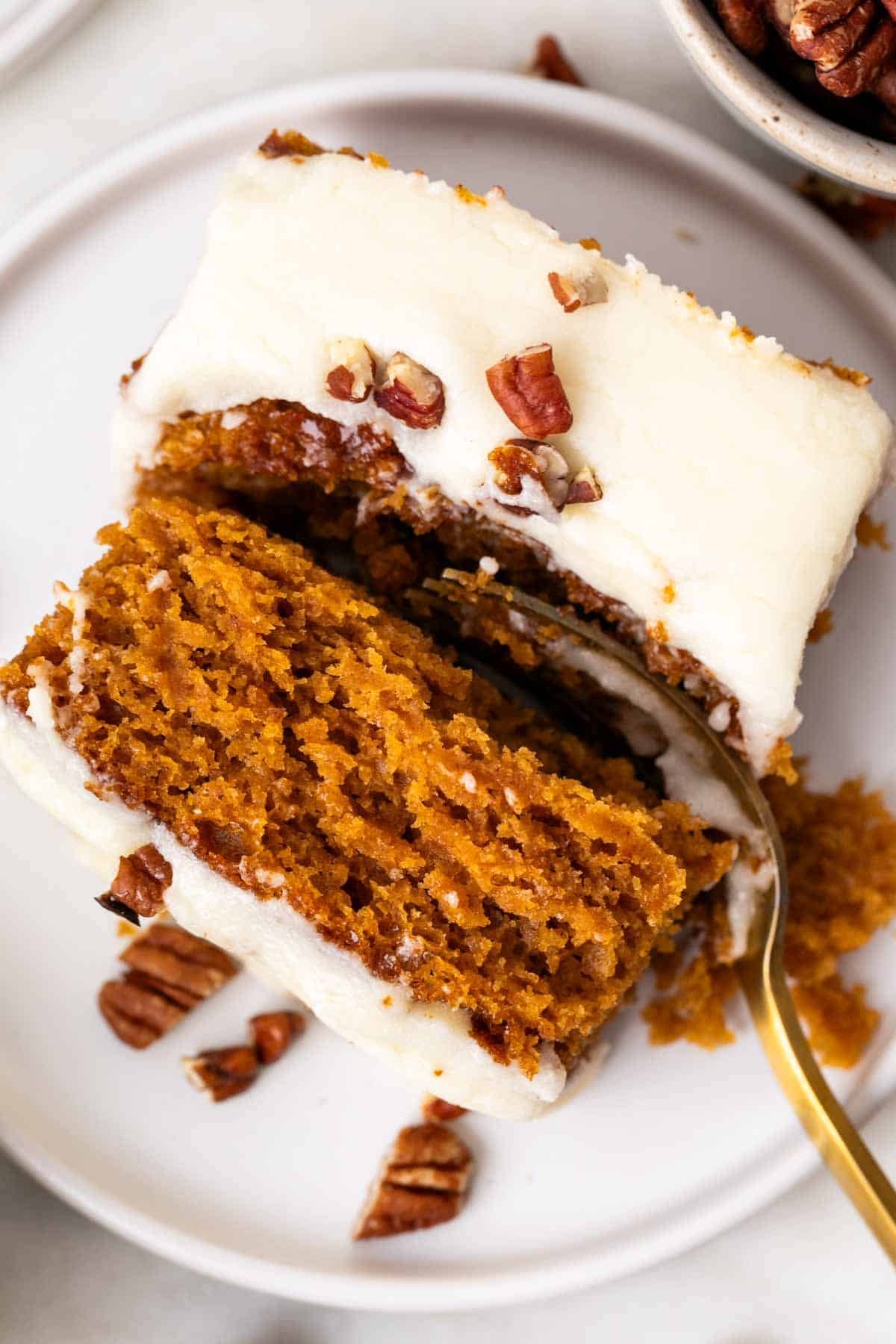 Slice of vegan pumpkin cake on a plate with a fork cutting through.