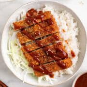 Japanese-style tofu katsu bowl with rice, cabbage, and sesame seeds.