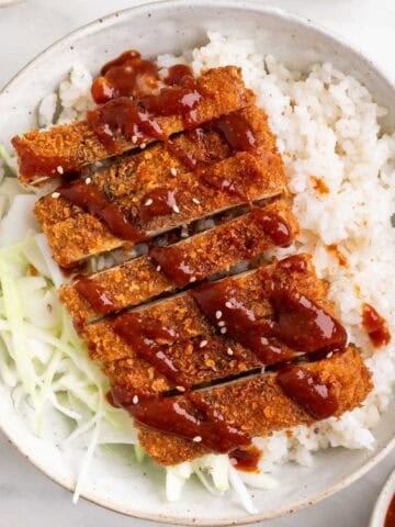 Japanese-style tofu katsu bowl with rice, cabbage, and sesame seeds.