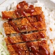 Bowl filled with rice, tofu katsu, cabbage, and sesame seed topping.