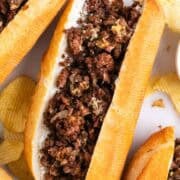 Vegan Philly cheesesteak sandwiches with chips on the side.