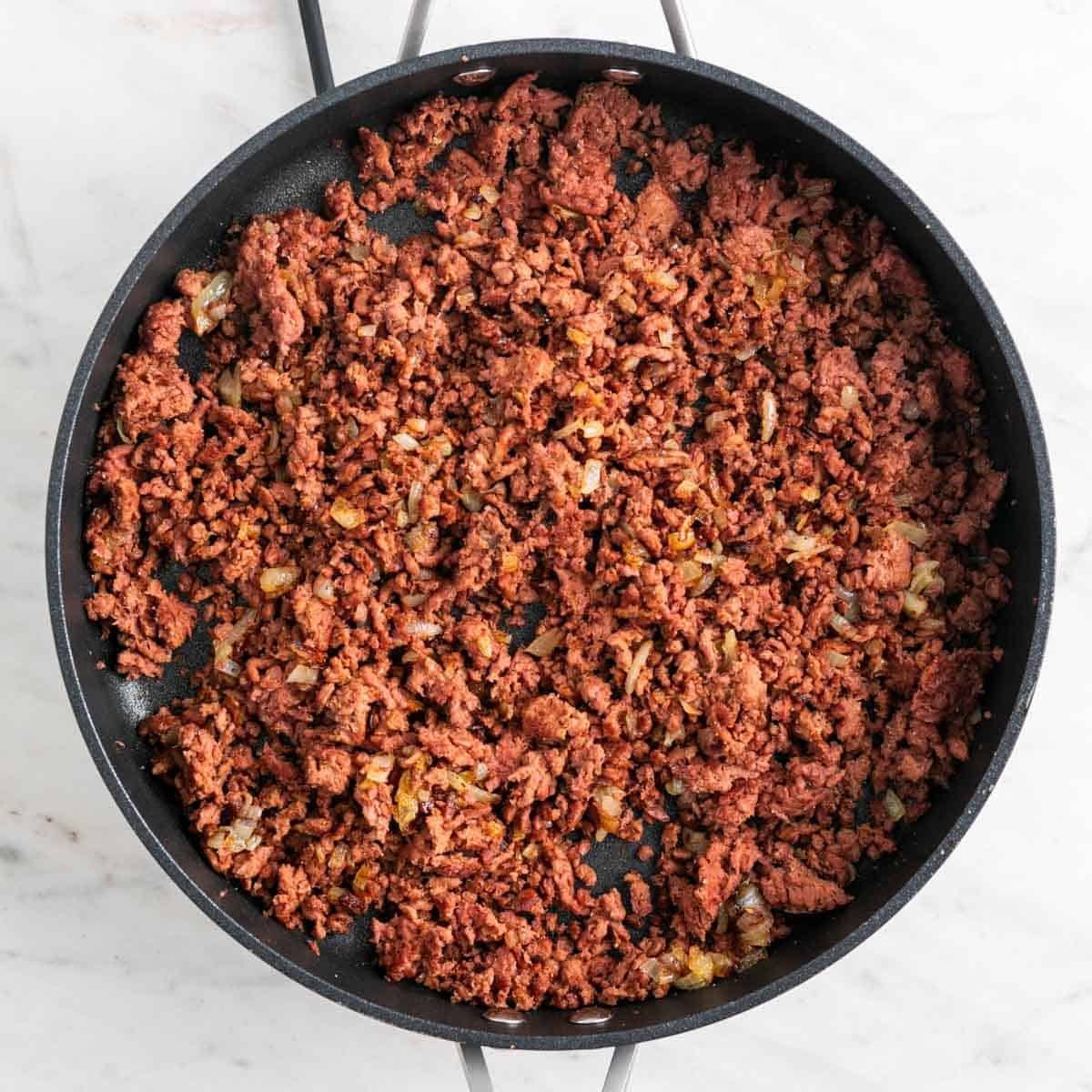 Cooked vegan ground beef and caramelized onions in a skillet.