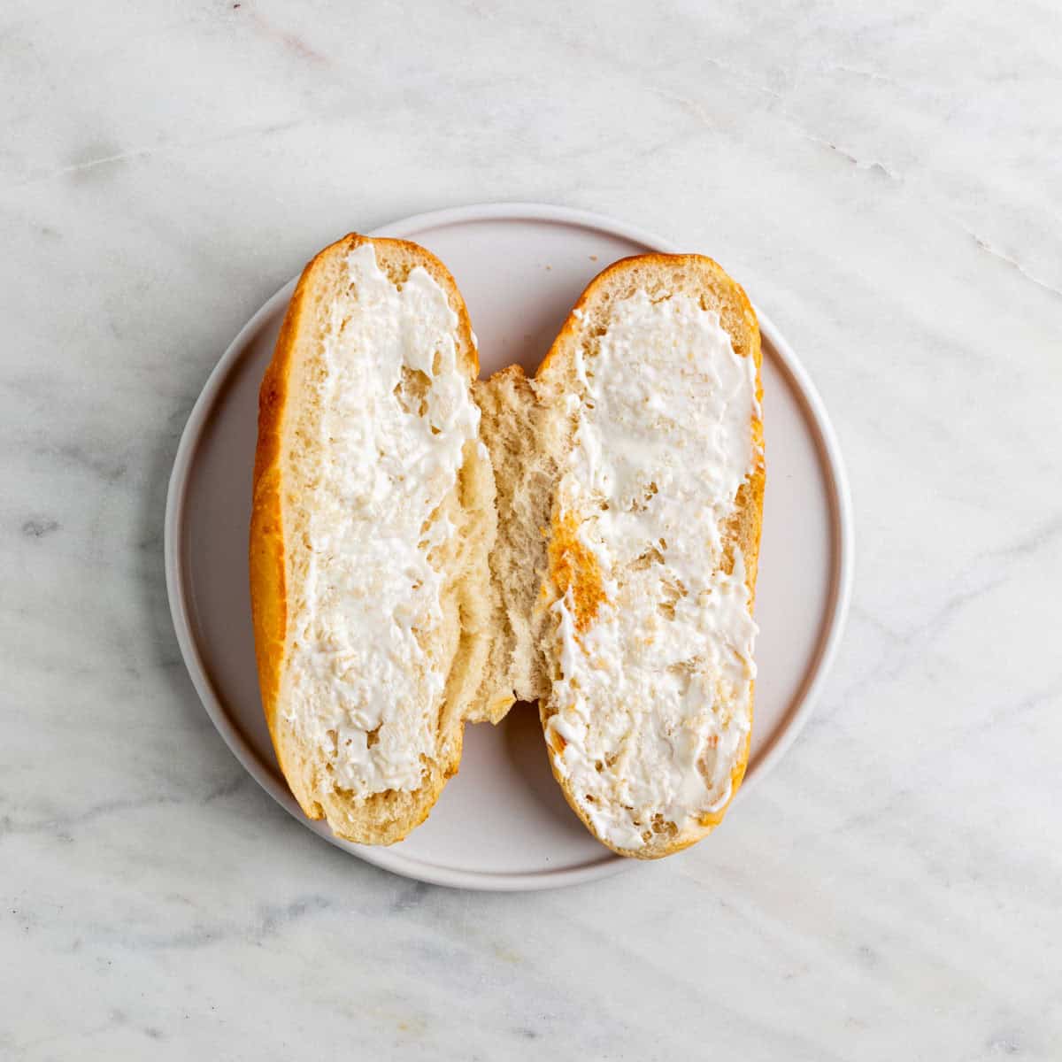 Toasted sandwich roll spread with vegan mayo.