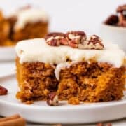 Vegan pumpkin cake topped with cream cheese frosting and pecans.