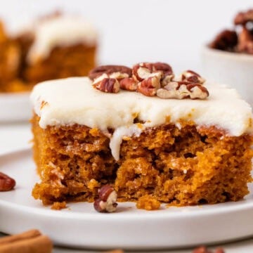Vegan pumpkin cake topped with cream cheese frosting and pecans.