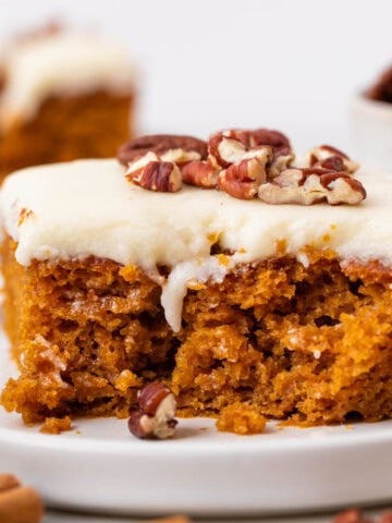Vegan pumpkin cake topped with cream cheese frosting and pecans.