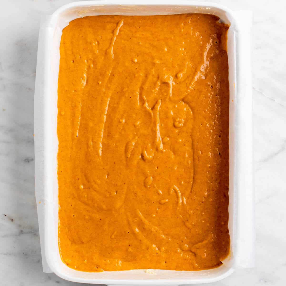 Vegan pumpkin cake batter in the lined baking dish.