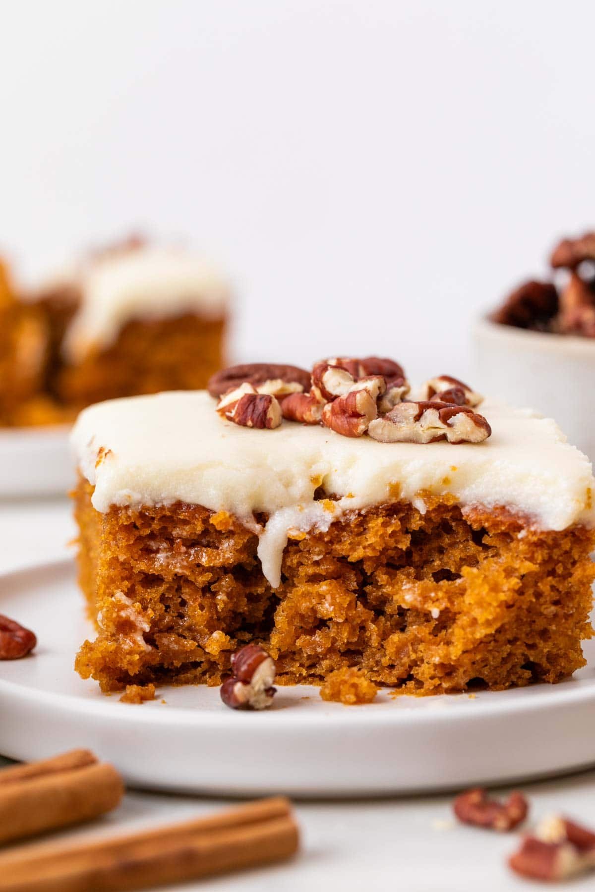 Vegan pumpkin cake with frosting and pecans on top.