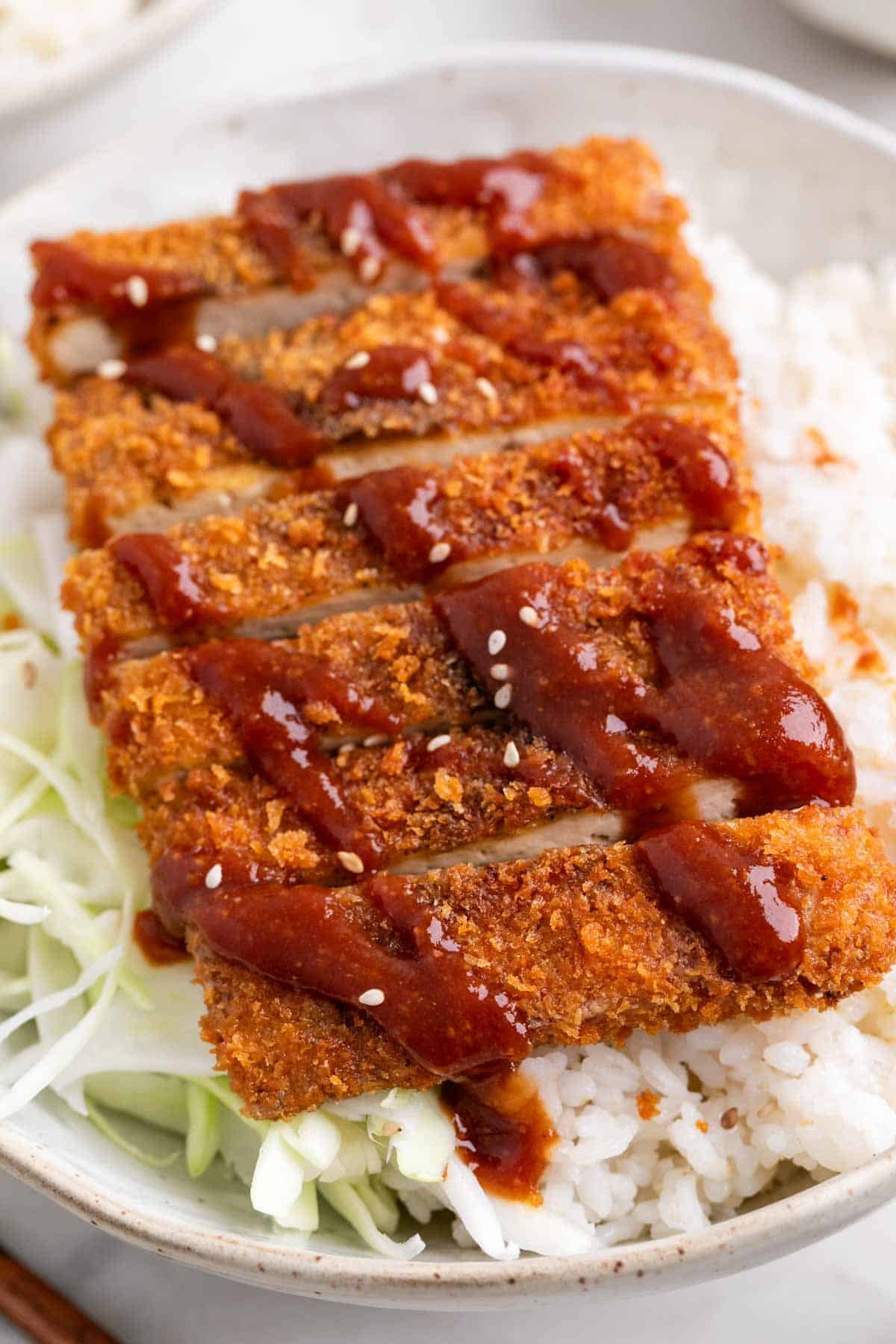 Tofu katsu with rice, shredded cabbage, and sesame seeds in a bowl.