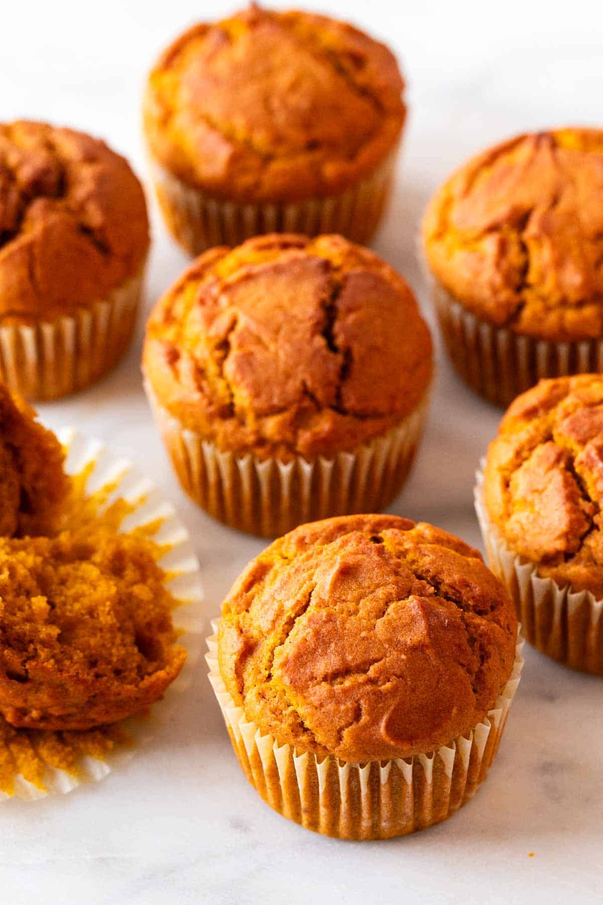Several vegan pumpkin muffins with a sliced one.
