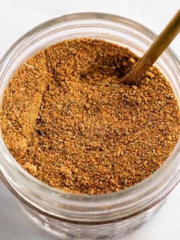 Homemade chicken seasoning blend in a jar with a spoon.