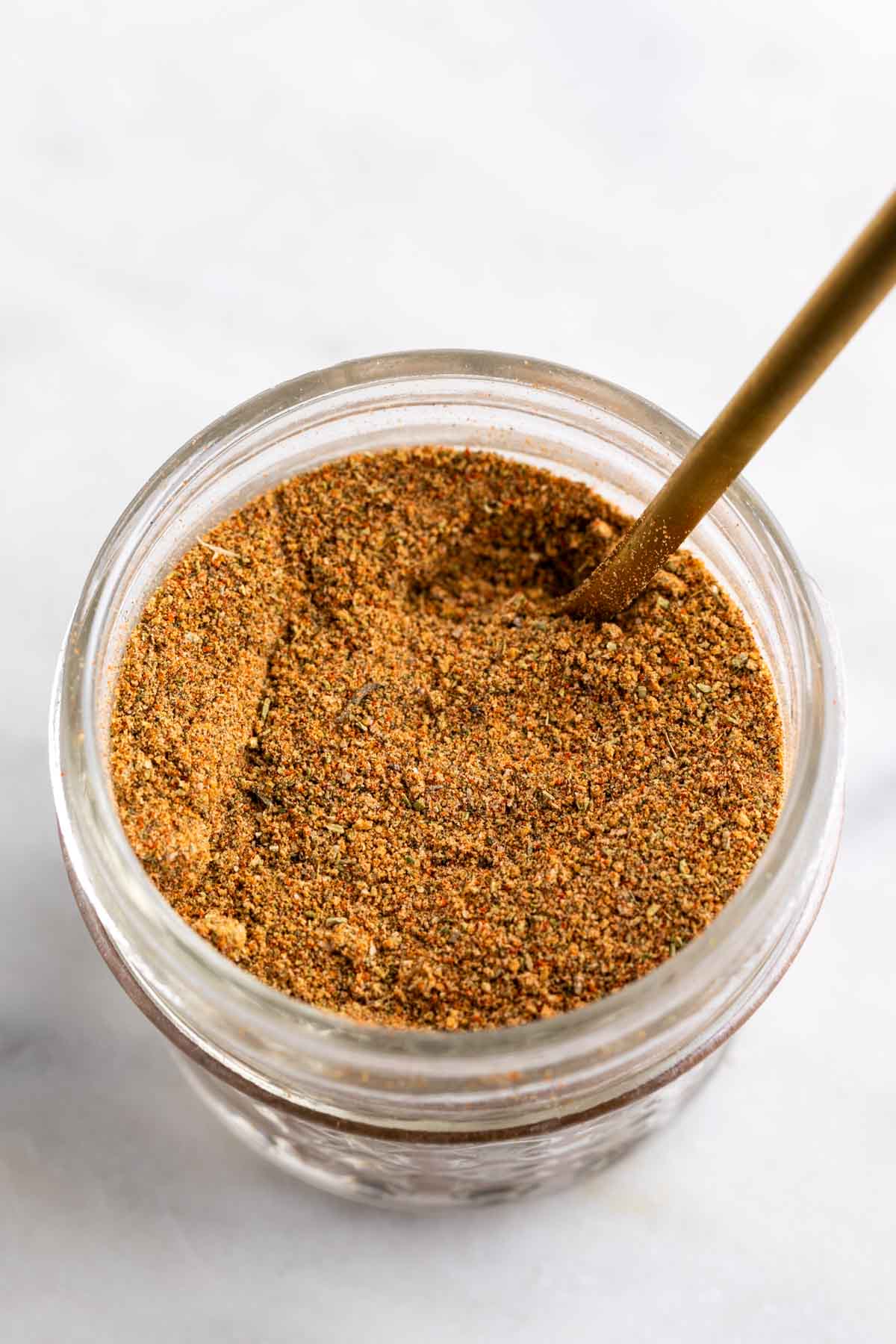 Jar of chicken seasoning with a spoon.