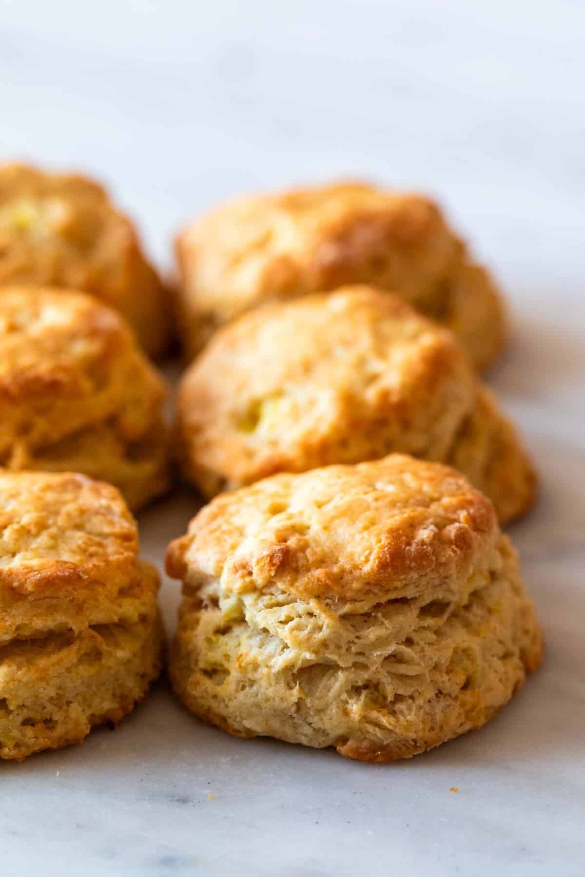 Six golden vegan biscuits on marble, viewed from the side.