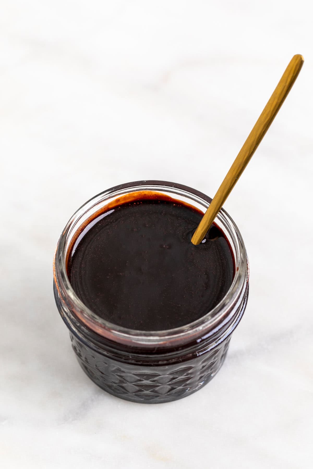 Vegan chocolate sauce in a jar with a spoon.