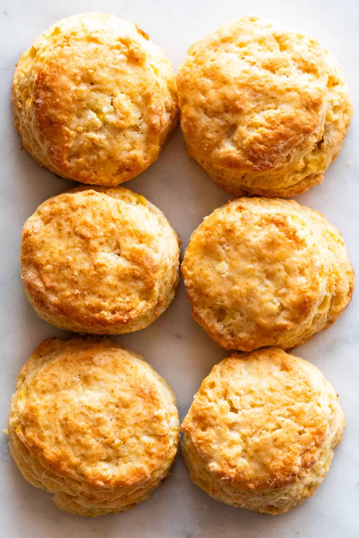 Six golden vegan biscuits on a marble surface.