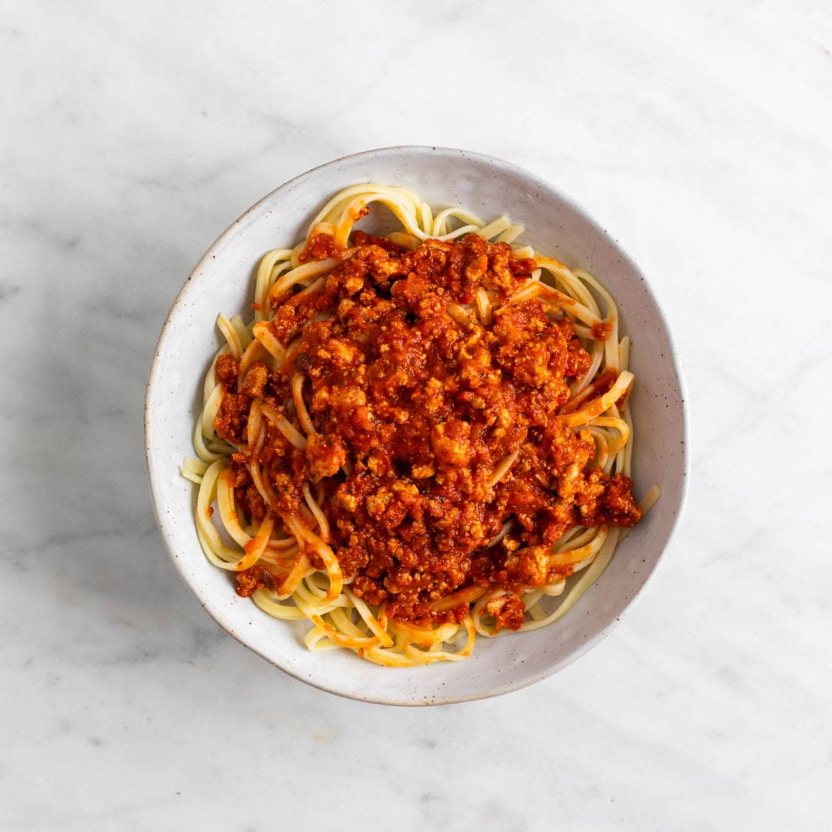 Tofu bolognese sauce over spaghetti in a bowl.