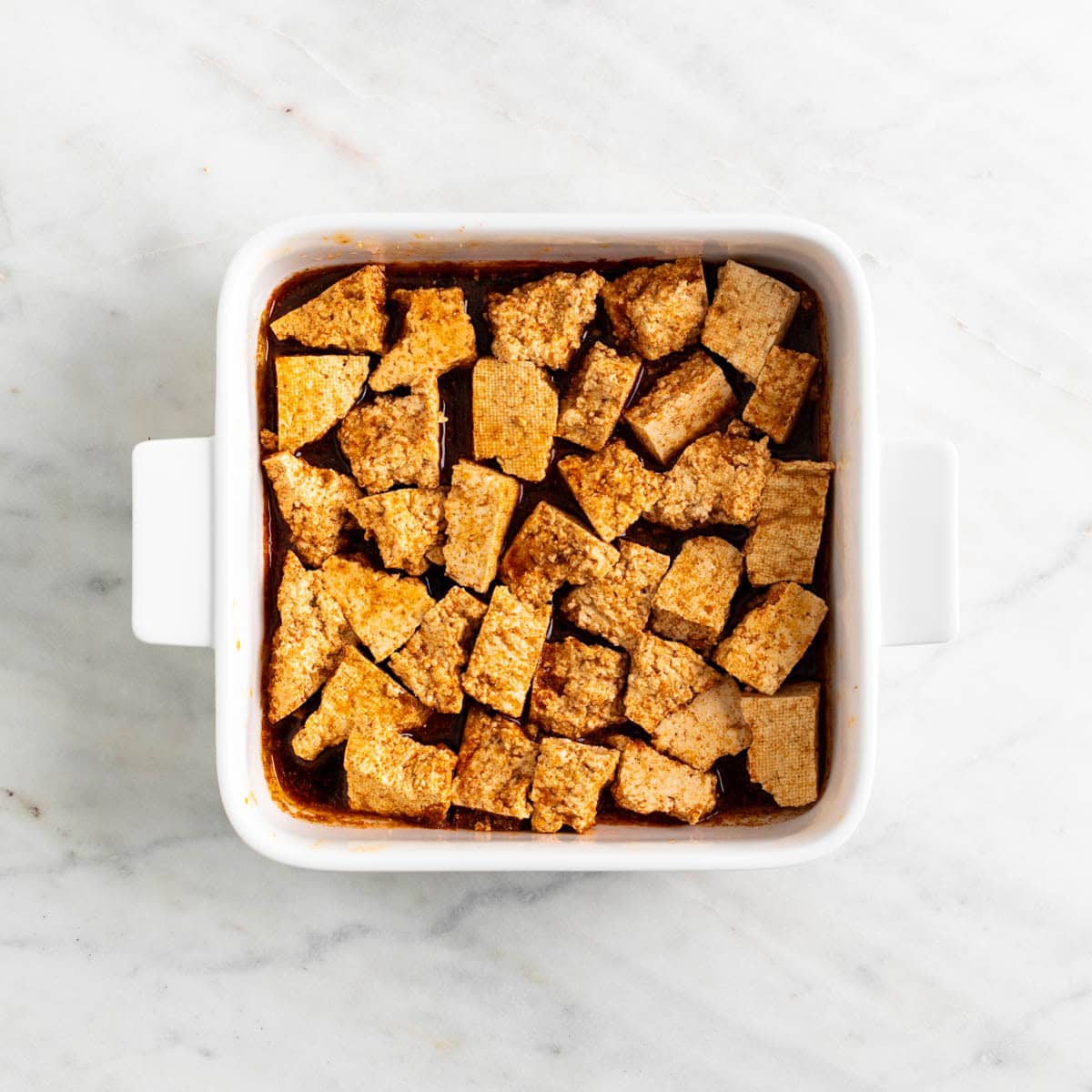 Tofu chunks marinating in the baking dish.