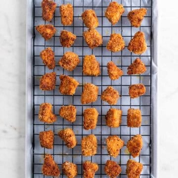 Cooked tofu nuggets on a wire rack on a lined baking sheet.