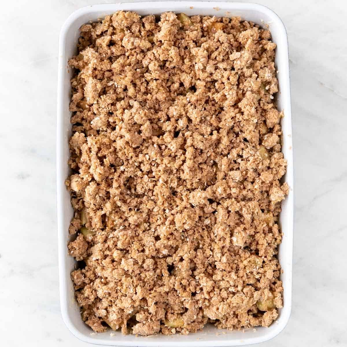 Baking dish with vegan apple crisp before baking.