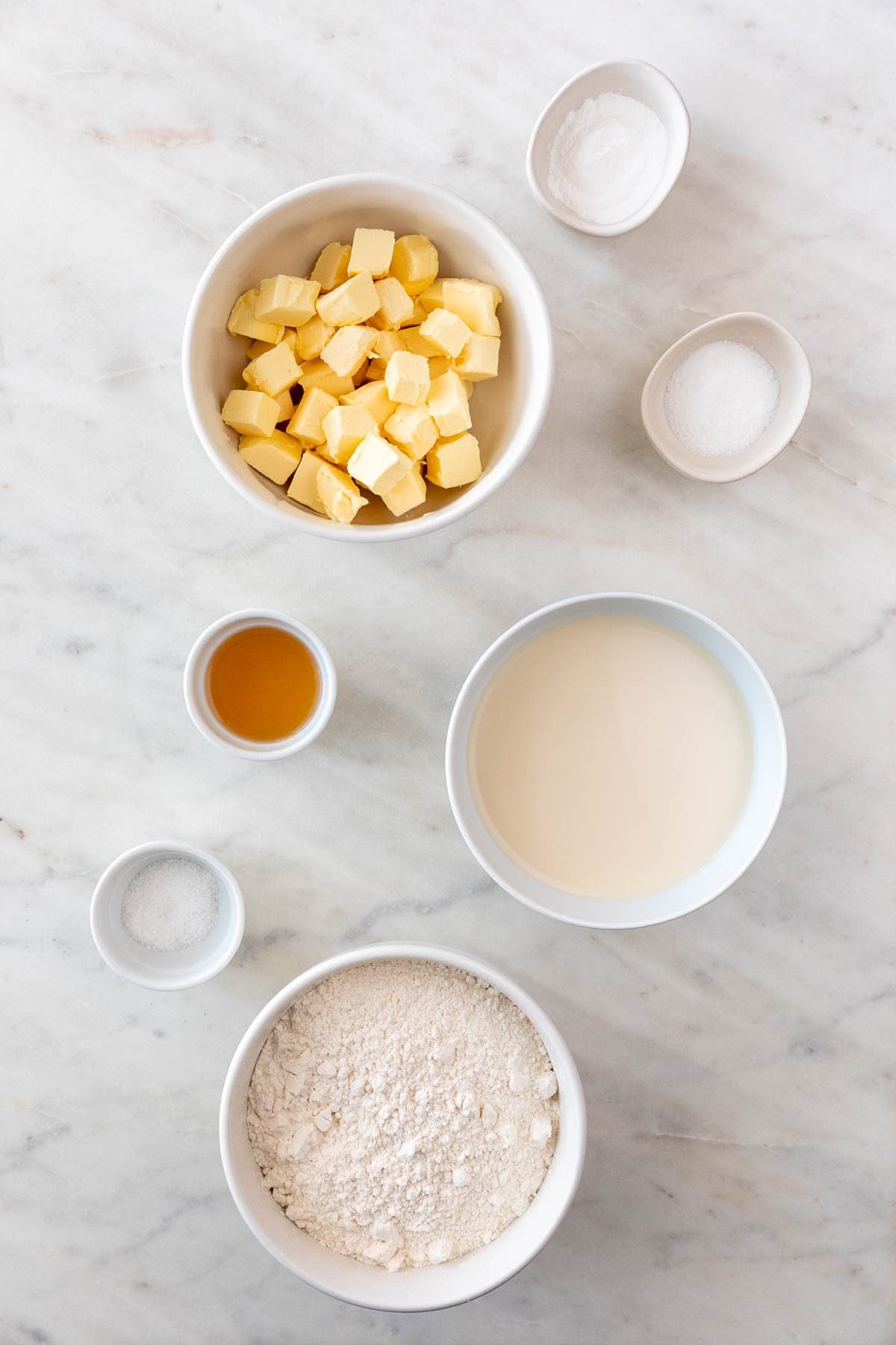 All 7 ingredients for vegan biscuits, measured and arranged in small bowls.