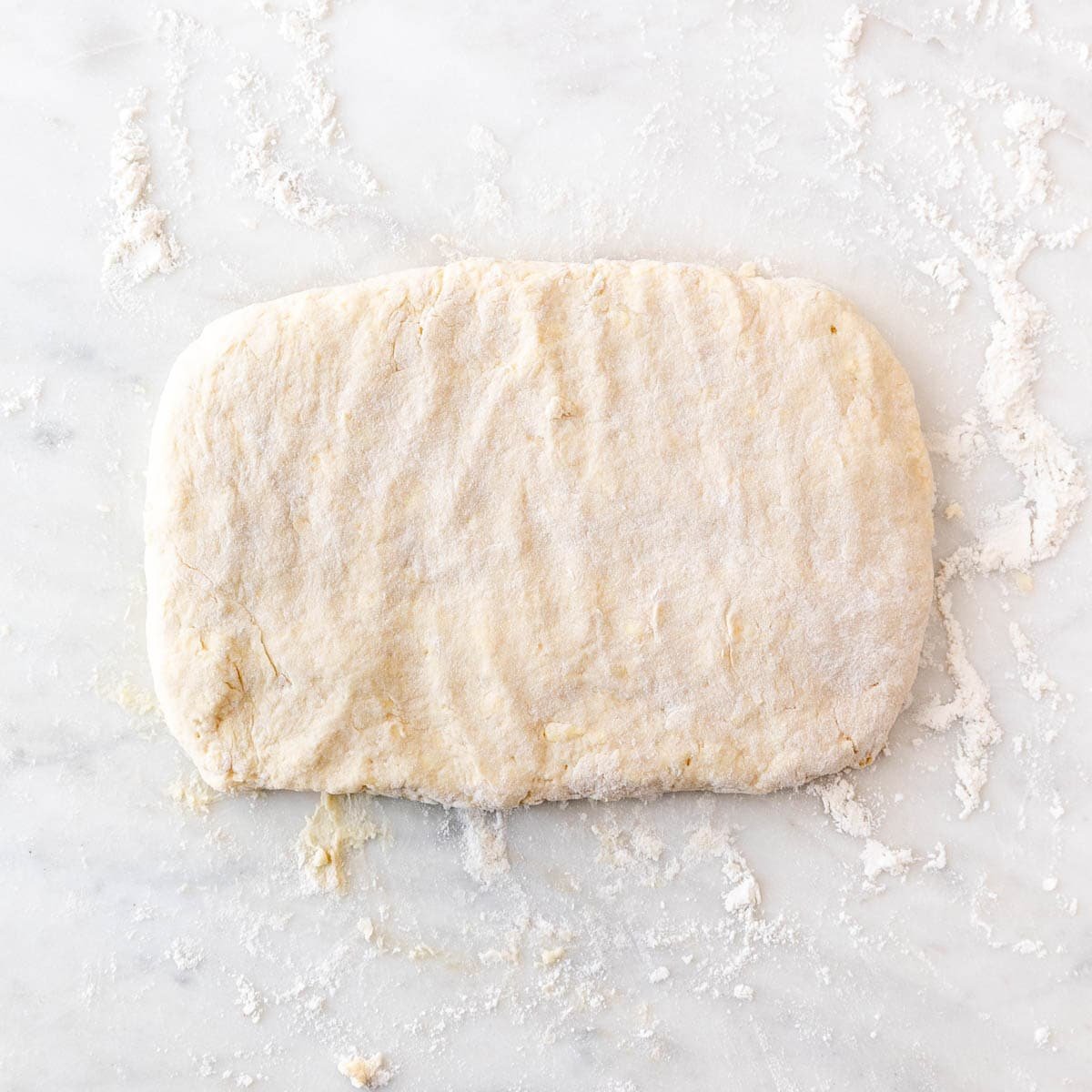 Biscuit dough flattened into a rectangle after the first fold.