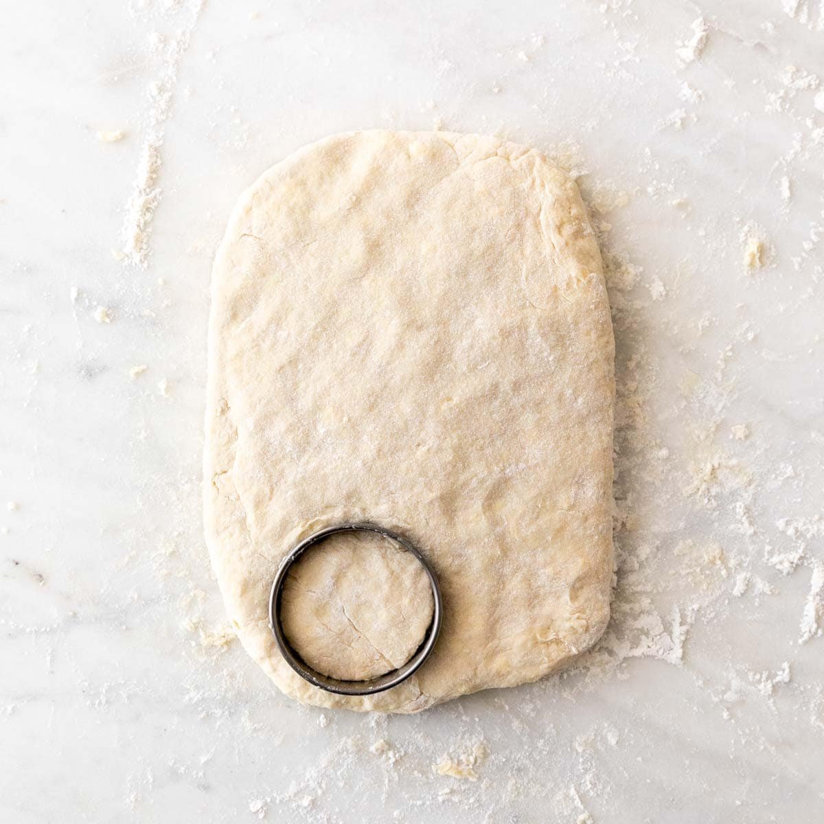 Cutting the first round biscuit using a metal biscuit cutter on the dough.