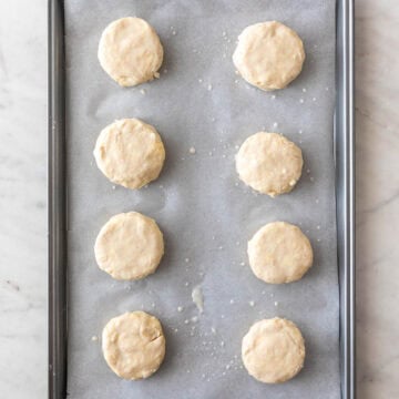 Unbaked vegan biscuits arranged on a baking sheet, ready for the oven.