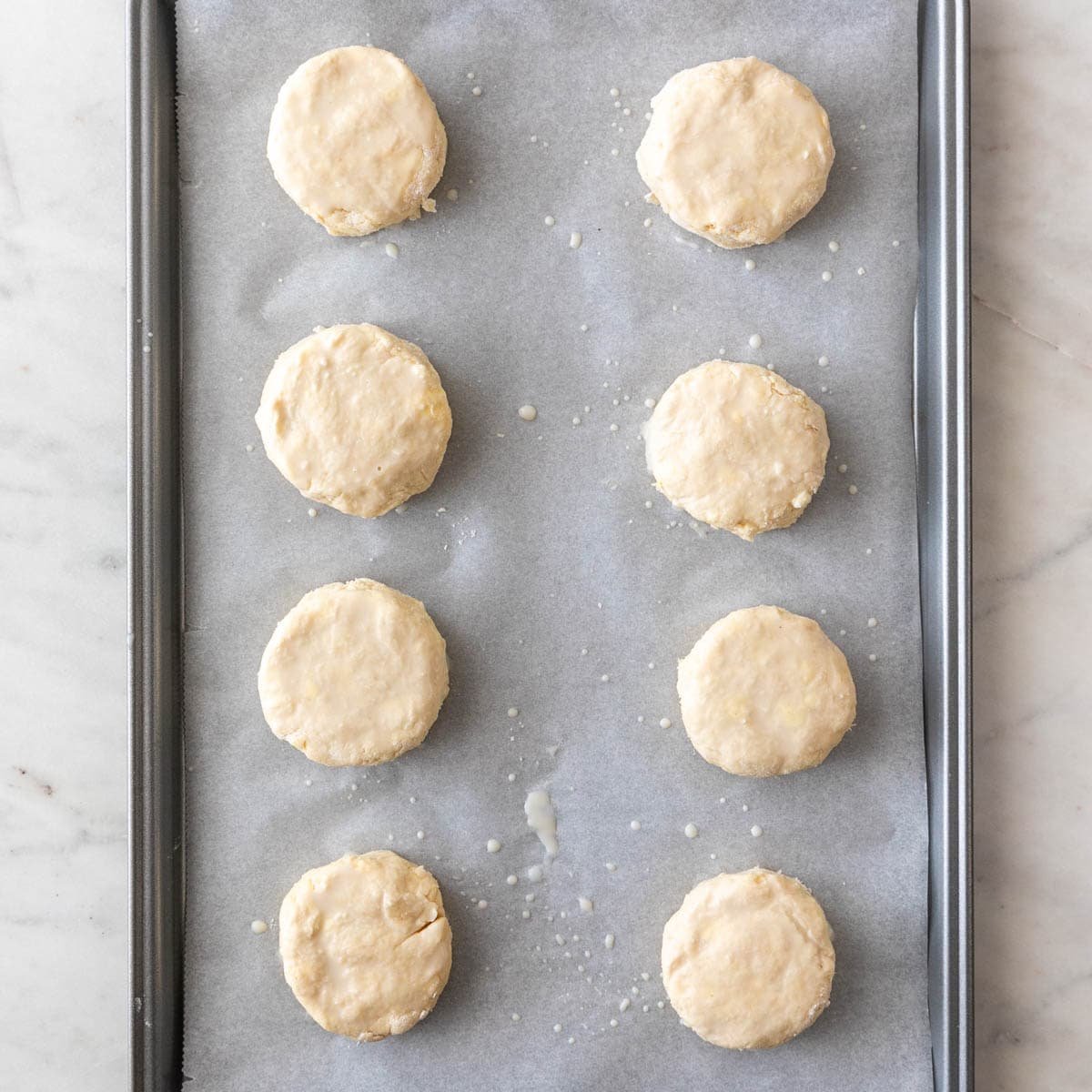 Unbaked vegan biscuits arranged on a baking sheet, ready for the oven.