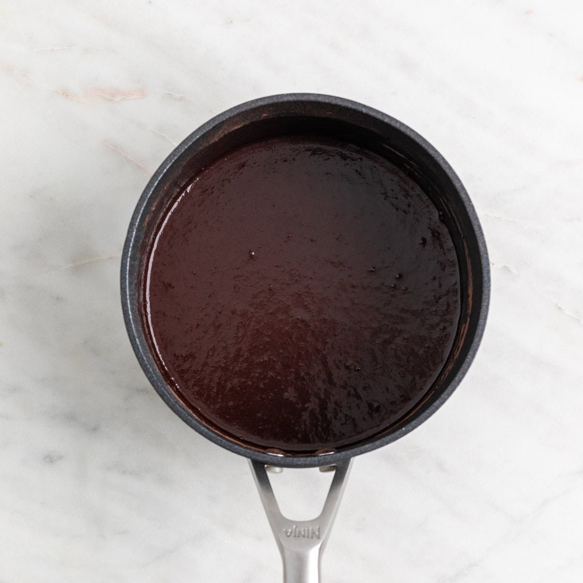 Ingredients for vegan chocolate sauce mixed in a saucepan.