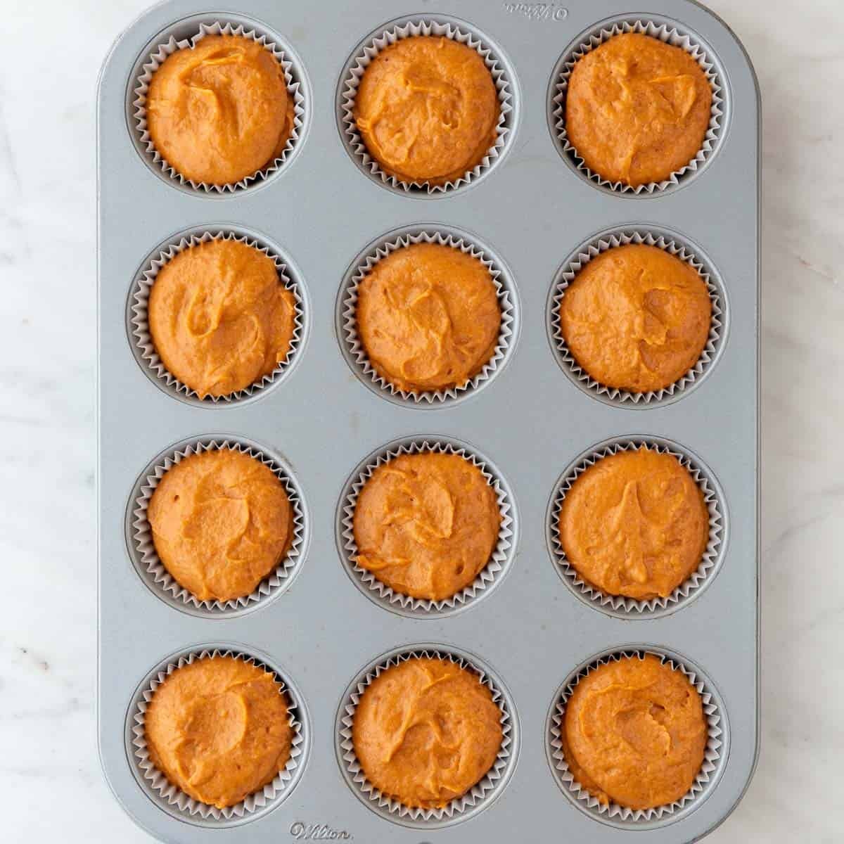 Muffin pan with vegan pumpkin batter.