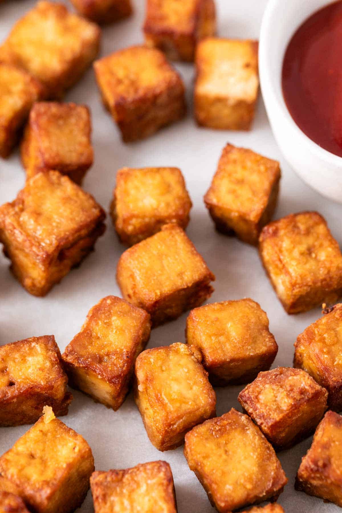 A plate of air fryer tofu on a white background with a side of ketchup.